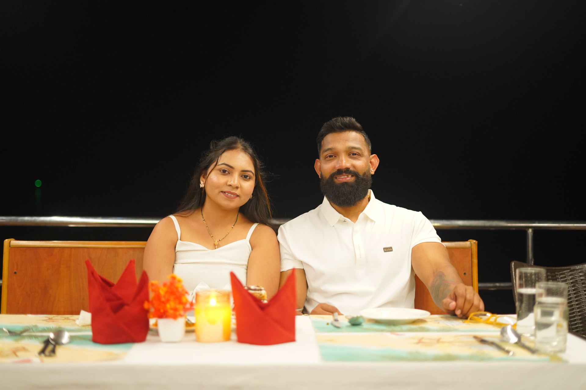 A couple enjoying a candle-lit dinner on the open deck at night