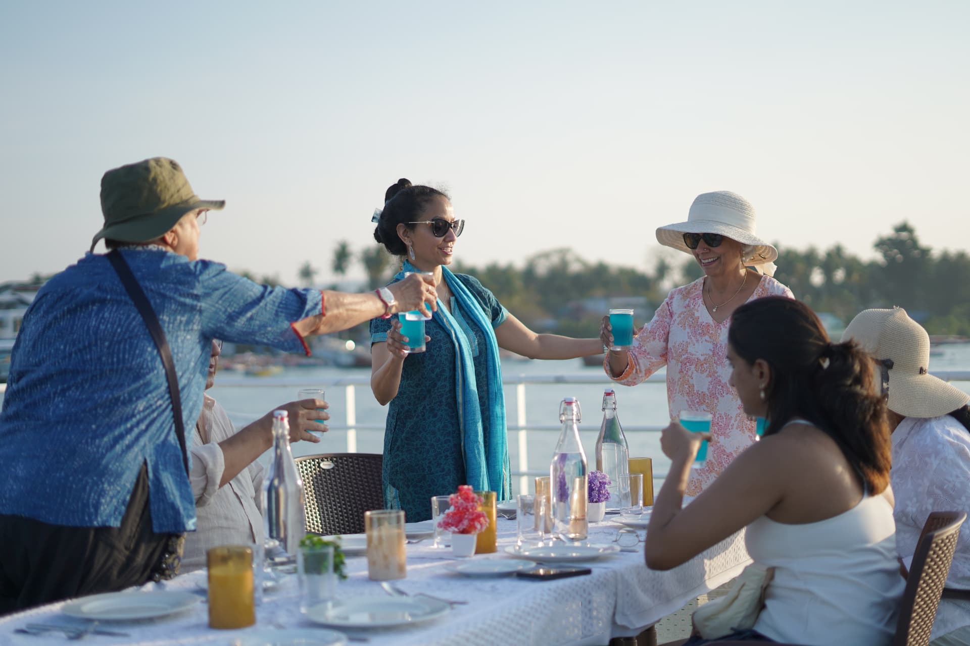 Guests raising a toast with welcome drinks on deck at golden hour