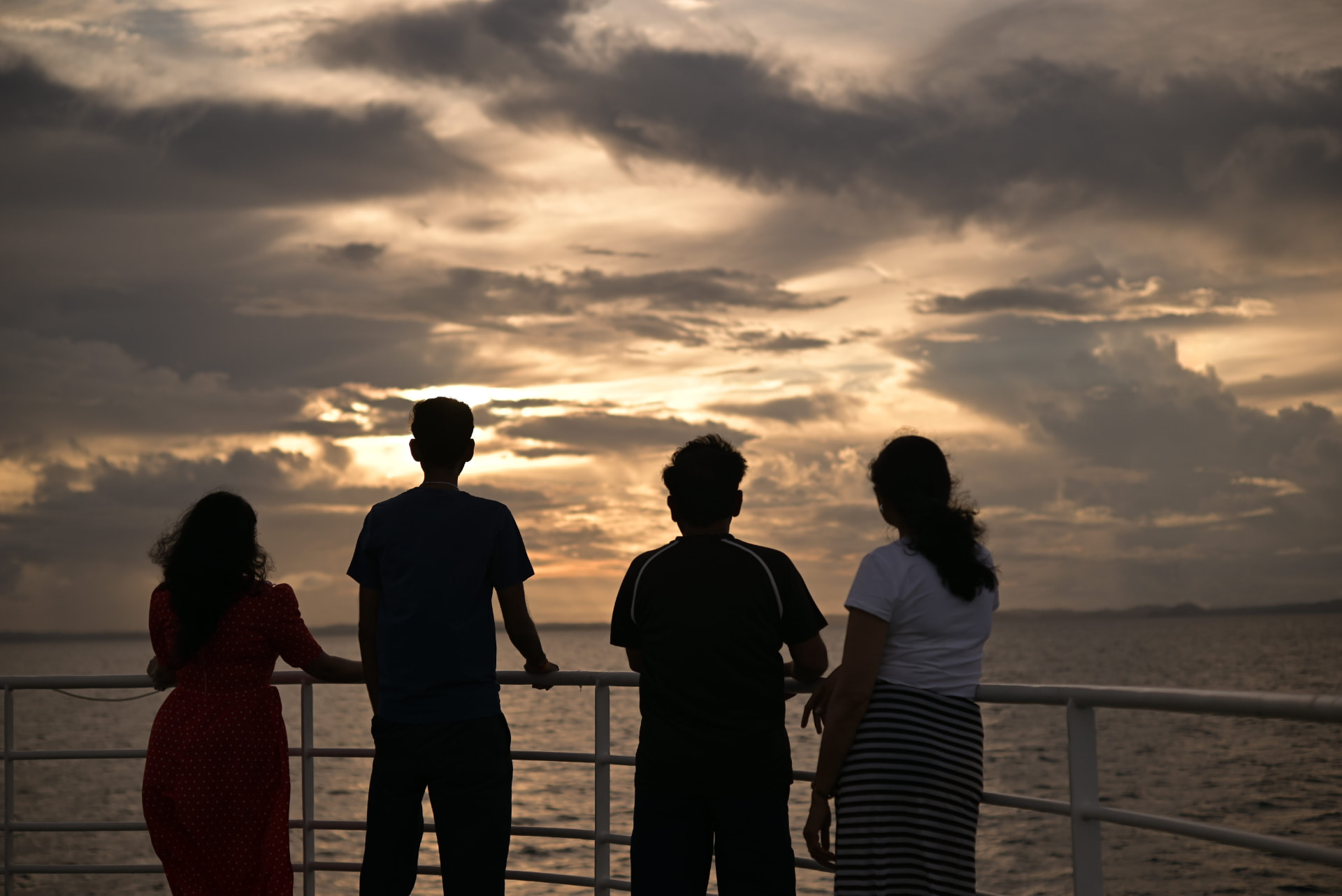 Guests silhouetted against the sunset sky from the cruise deck