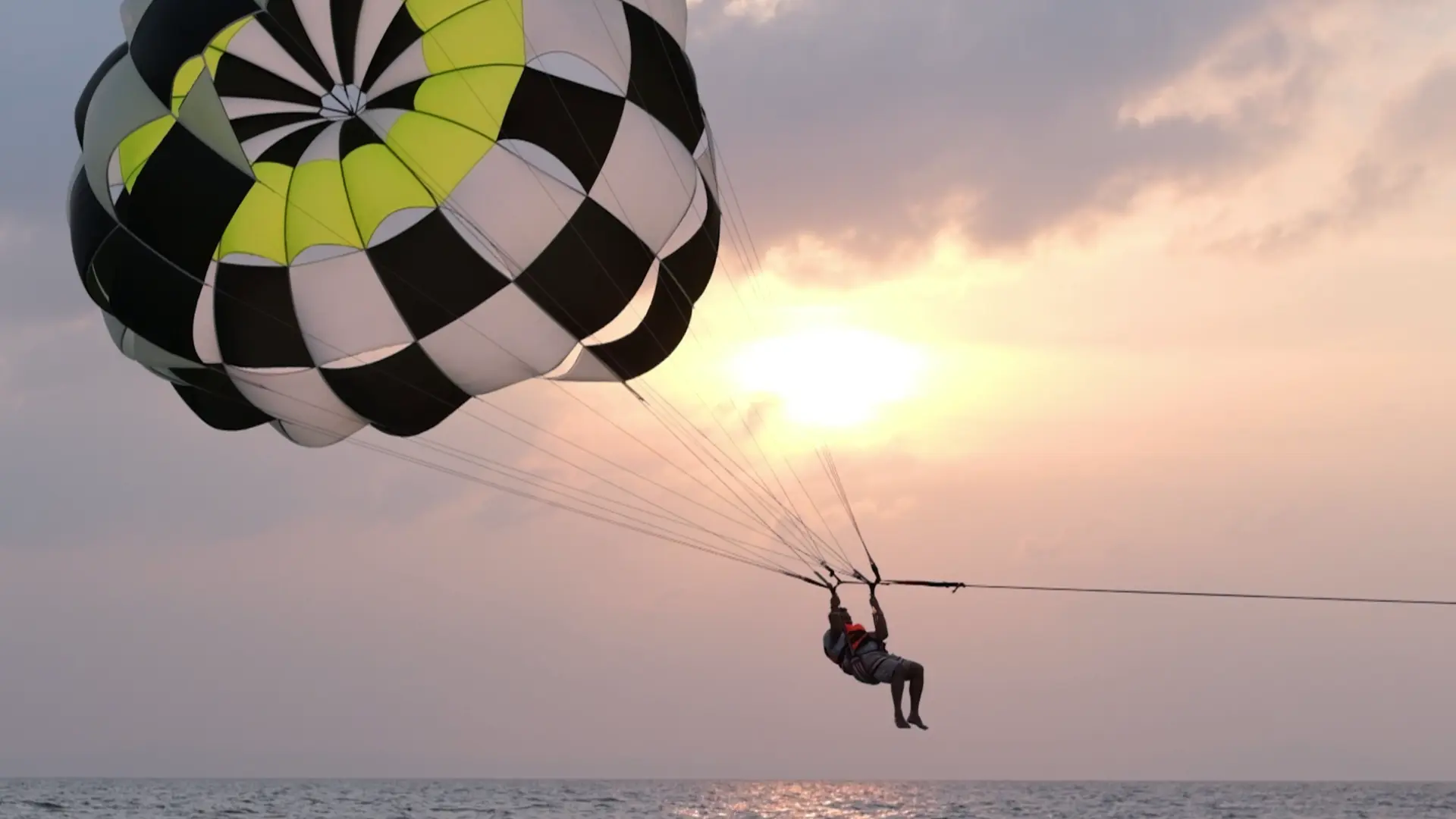 Parasailing over the sea against the setting sun