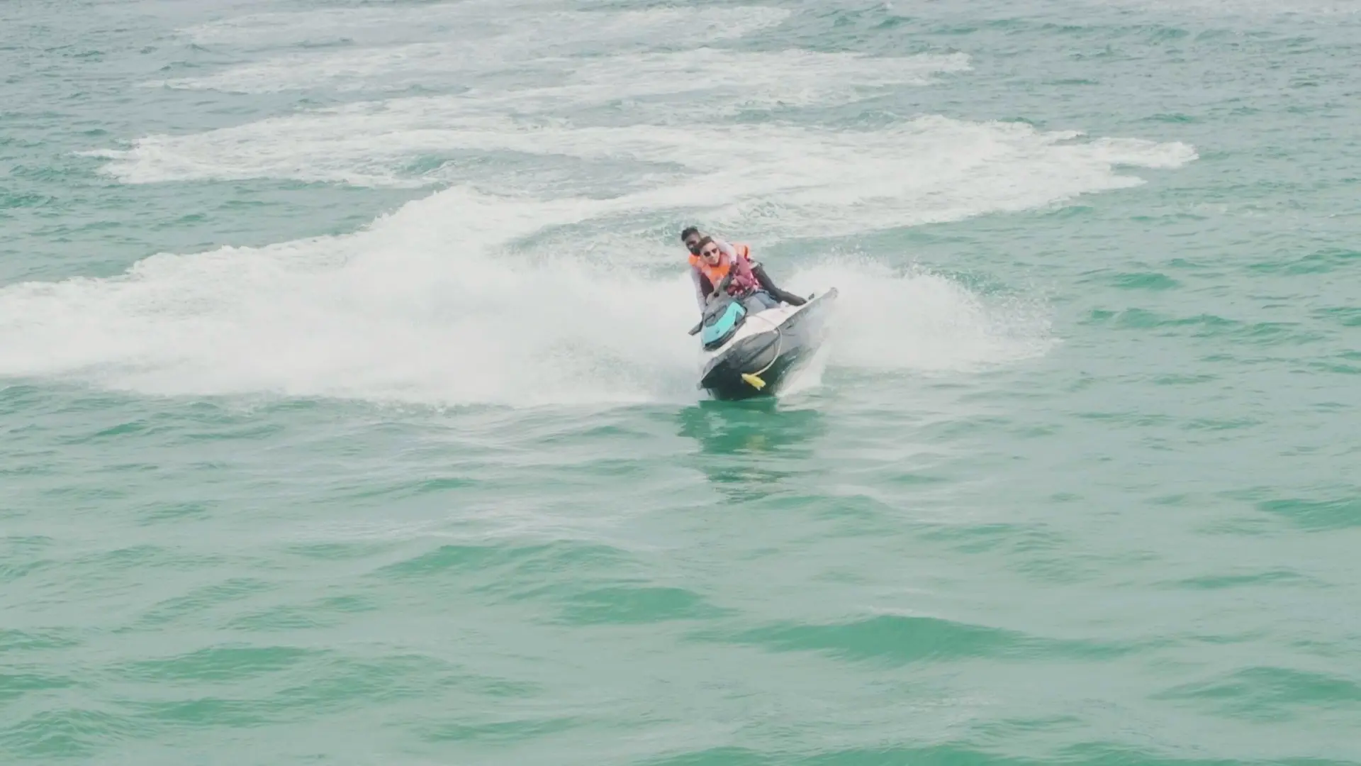 A couple riding a jet ski across turquoise waters